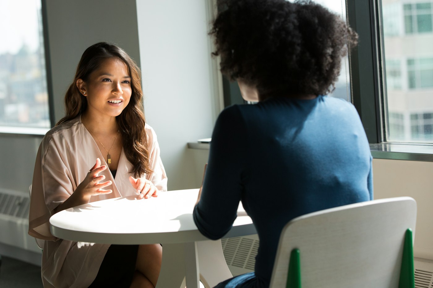 A retirement planning consultant in conversation with a client at a bright office table in Chiang Mai.